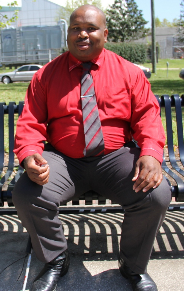 Walter Blackmon sits on a park bench while smiling at the camera.